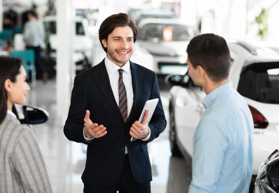 Car dealer talking with clients selling them automobile